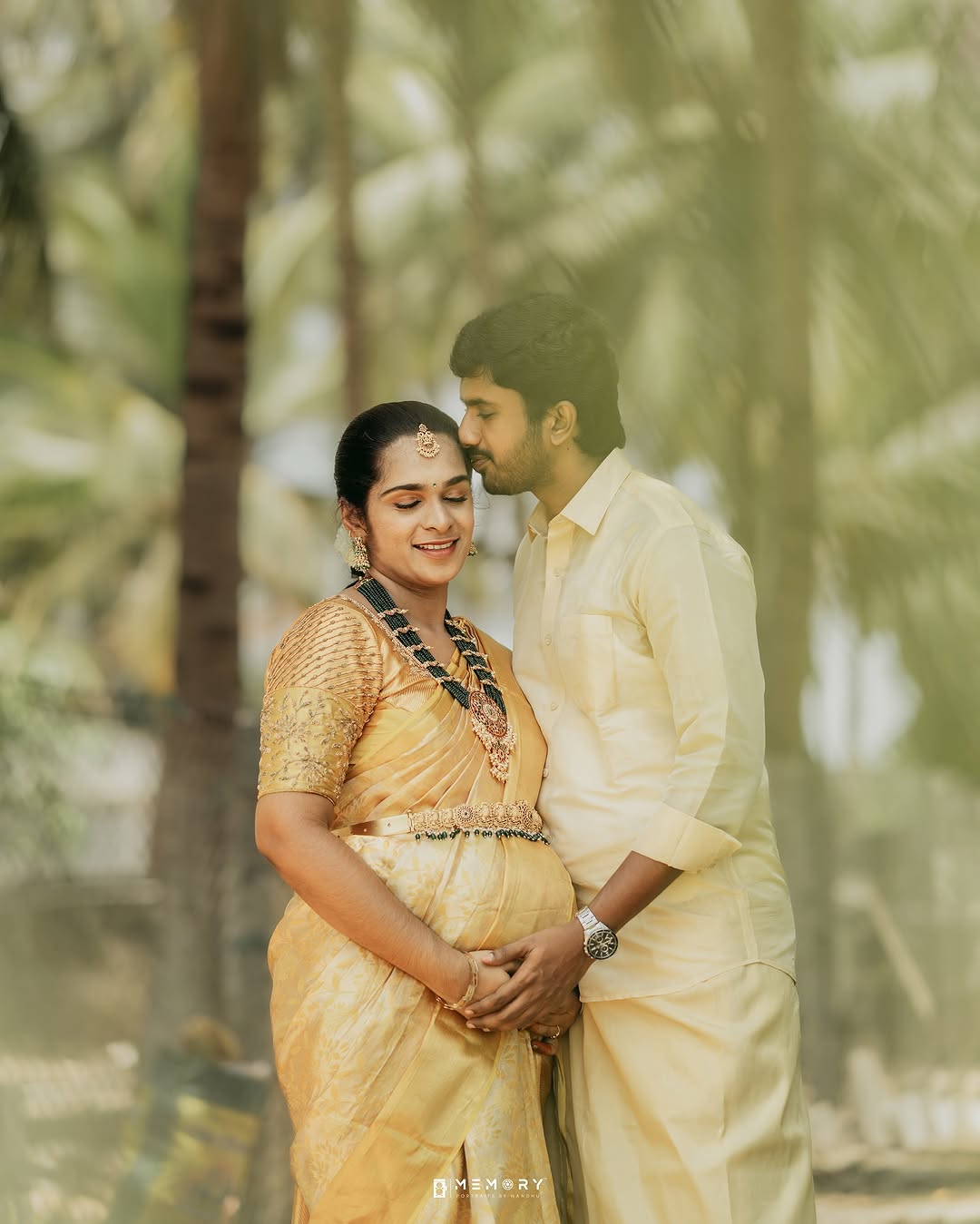 Expectant parents in silk, hands resting on the bump