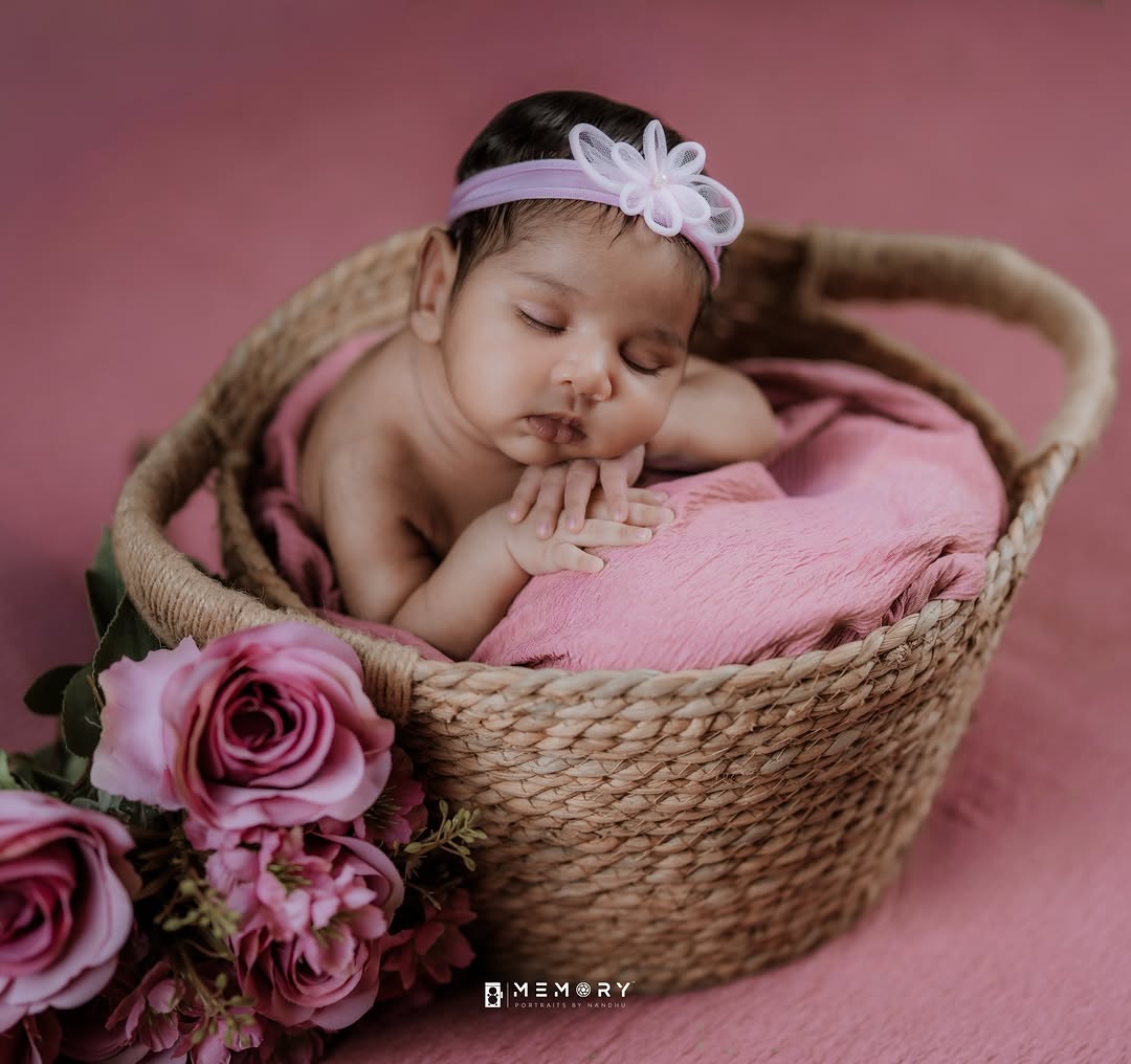 Sleeping newborn in a basket with pink roses