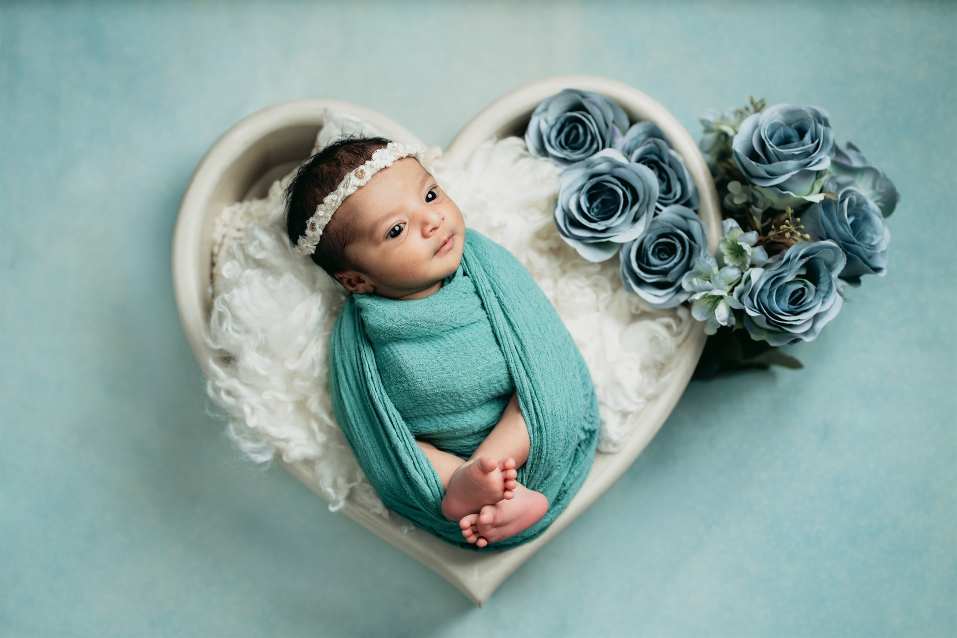 Newborn in a heart-shaped bowl with blue roses